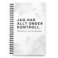 Notebook med texten "Jag har allt under kontroll, definitionen av allt kan diskuteras" – spiralbunden med prickade sidor.
